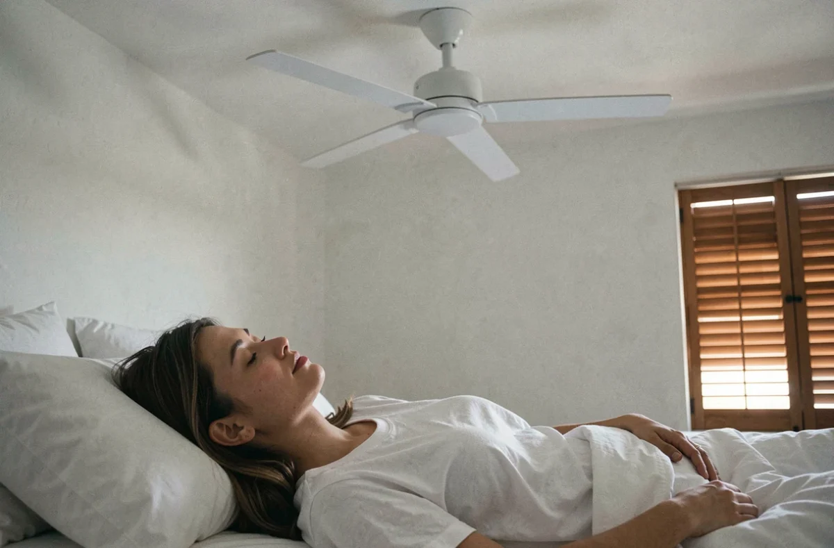 Femme endormie dans une petite chambre équipée d'un ventilateur de plafond silencieux pour un sommeil confortable